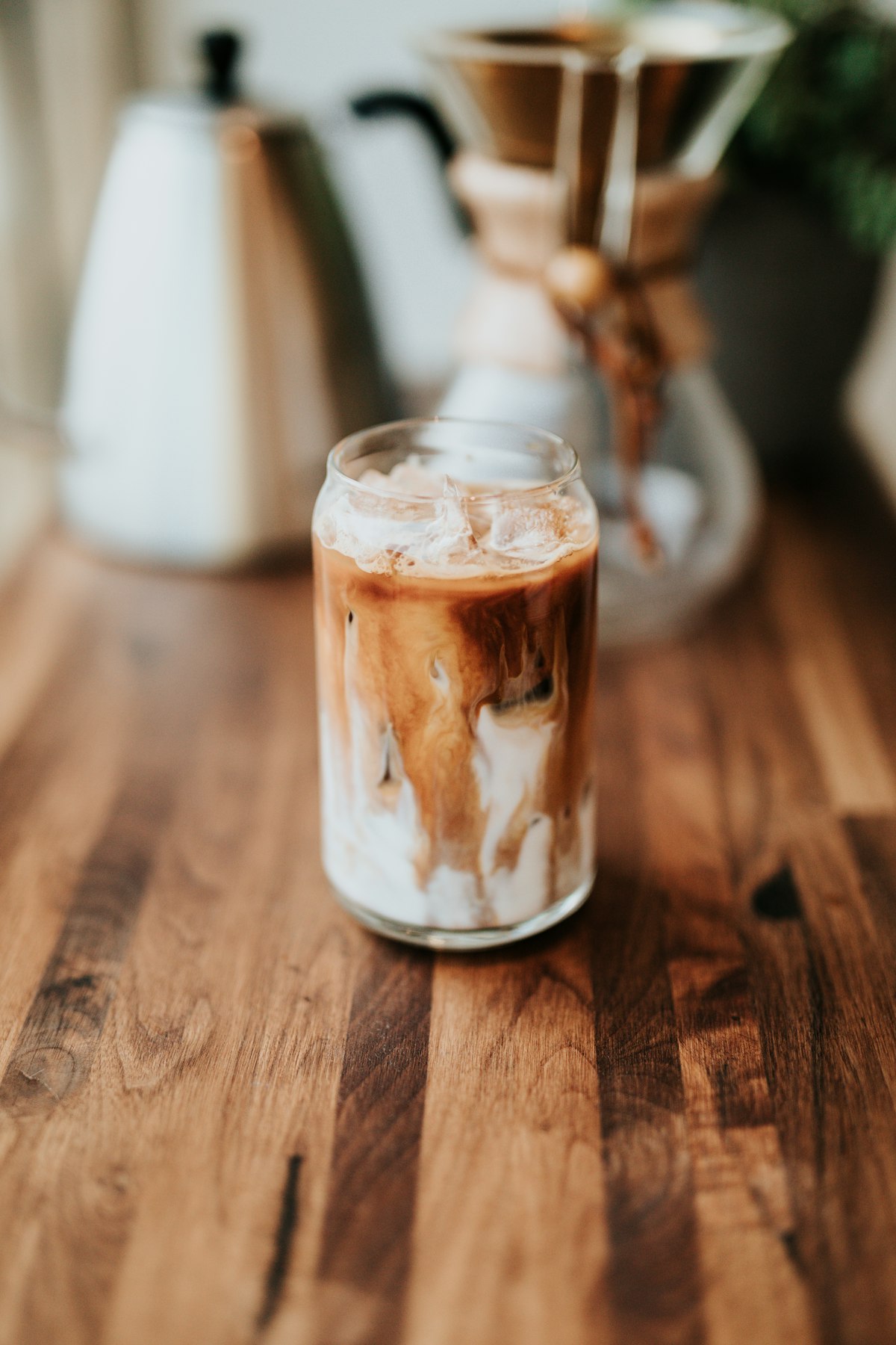 Classic iced latte with milk swirl in a glass on a wooden table
